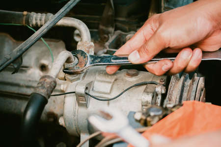 Young mechanic working use a wrench and fixing old carの写真素材