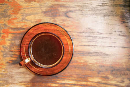 Top view,Hot coffee cup on glass cup on wooden table background.の写真素材