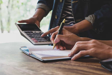 Asian young man and woman sitting pointing studying examining and using calculator tutor Math books...
