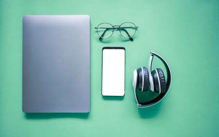 laptop and vintage glasses, headphones and mobile phones leave white screen empty space mock-up for text. The layout of the elements Concept of music and podcastingの写真素材