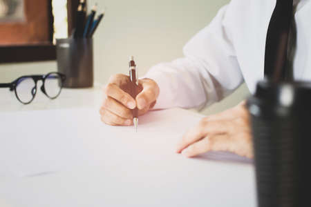 businessman sitting chair writing and signature on the paper document is working in his officeの写真素材