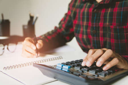 businessman hand using calculator Calculating bonus(Or other compensation) to employees to increase...