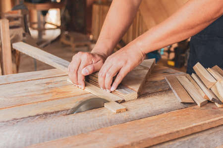 Close up, carpenter man cutting a plank of wood in the working using a circular saw in workshop.の写真素材