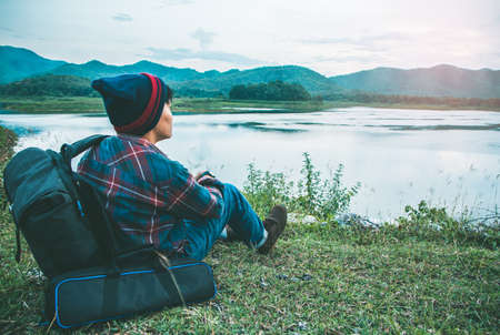 Asian man relaxing in a bag on green grass camping travel vacations in mountains and river Lifestyle concept adventure outdoor wild natureの写真素材