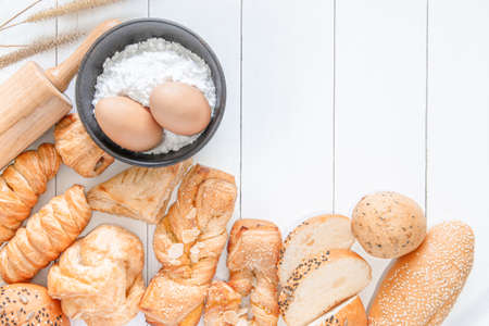 Fresh fragrant baked bread, pie, bread rolls and white sesame on wooden table background, top view copy space for text.の写真素材