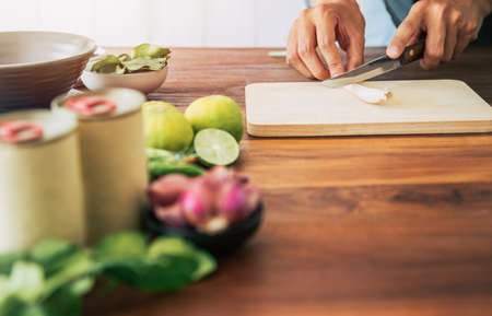 people are slicing lemongrass on a table with vegetables,shallots,chilies, lemons, kaffir lime leaves to make canned fish salad menu Is simple menu.Thai food.Cooking preparation in the kitchen at homeの写真素材
