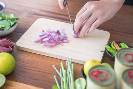 people are slicing shallots on table with vegetables,lemongrass,chilies, lemons, kaffir lime leaves to make canned fish salad menu Is simple menu.Thai food. Cooking preparation in the kitchen at homeの写真素材