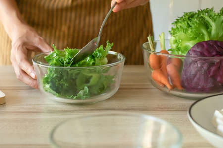 close up. hand cooking food, preparation menu salad, fresh lettuce on a cup with carrot and cauliflower on table kitchen at homeの写真素材