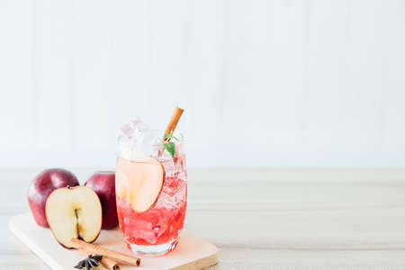 Red apple soda ice in a glass with the herb of cinnamon on wooden background