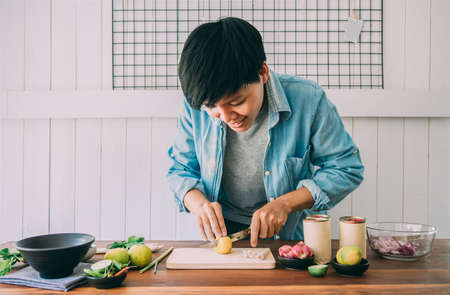 Smiling people are slicing lemons on a table with vegetables,chives, lemongrass, kaffir lime leaves to make canned fish salad menu Is simple menu. Thai food. Cooking preparation in the kitchen at homeの写真素材