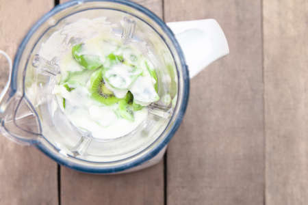 Fresh sliced kiwi fruit on electric equipment juice Yogurt smoothie ingredients and blender. Top viewの写真素材