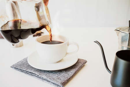 Close up. Hand of a barista poured water dripping hot coffee into the cup with smoke and equipment, tool brewing at kitchen homeの写真素材