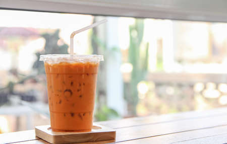Thai iced ice tea is placed on a wooden tray on a table, copy space for letters.