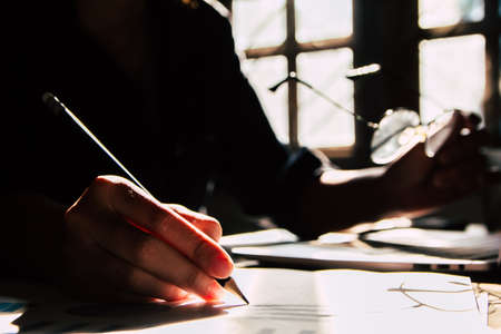 Asian young business man of student holding a pen writing letter on paper at home. silhouette photo