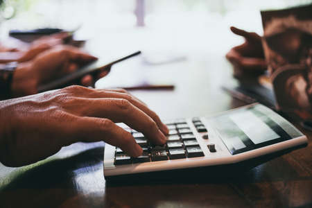 Close up man hand using calculator Calculating bonus(Or other compensation) to employees to increase...