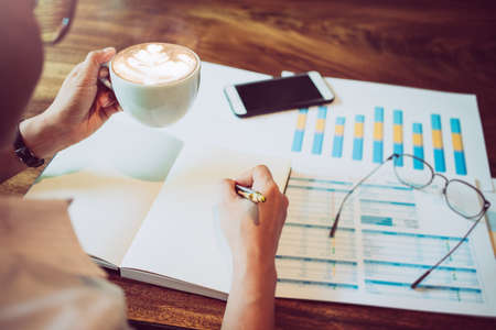 Asian businesswoman holding pen working, writing the report Calculate tax lead to liquidation on a...