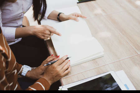 Asian young man and woman sitting pointing studying examining, Tutor books with friends Young students campus helps friend catching up and learning. People learning educationの写真素材