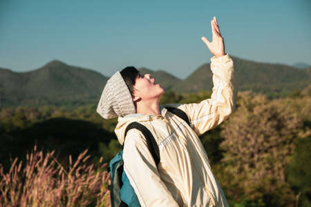 Asian young men 25-30 year selfie standing open arm hiking  happy with mountain blue sky landscape nature hiking outdoor at lamphun Thailandの写真素材