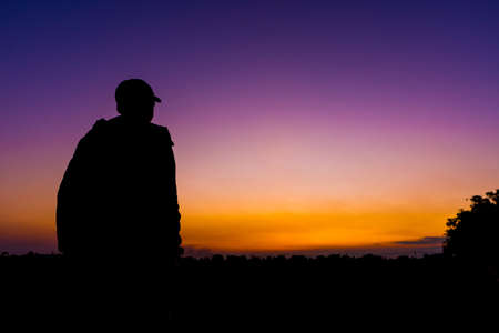 silhouette dark young man wearing a hat standing emotions with evening Twilight sky with cloud in...