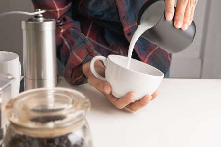 The professional of a barista poured milk. making latte coffee with equipment, tool brewing on bar at kitchen homeの写真素材