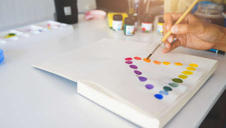 Close up hand of painter using brush painting and drawing wheel watercolour, studying and learning education ink art at home. Selective focusの写真素材