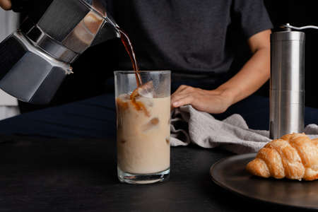 Man using italian classic Moka coffee pot pouring, coffee make cold of iced coffee in a glass and...