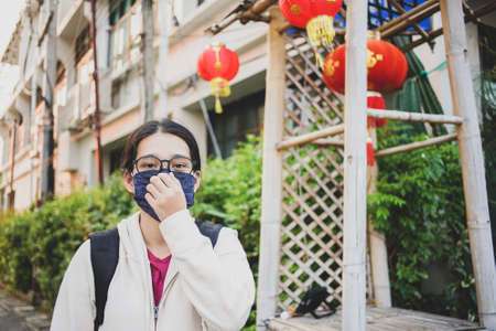 Asian woman wearing mask protective gear to protect coronavirus covid -19 and Air pollution pm2.5 concept, backpacker travel walking on the street at Thailandの写真素材