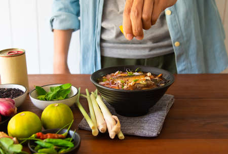 people are Squeezing fresh lemon juice. he is looking for recipes in the kitchen. reading cooking books of the food menu, salad canned fish cook. quarantine at home conceptの写真素材