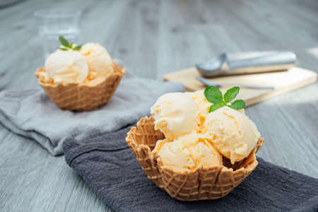 homemade Ice cream scoops with vanilla ice cream in a bowl with mint.