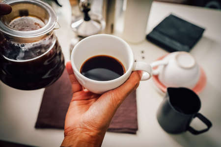Close up hand pouring coffee drip in a jug into the white cup with equipment, tool brewing with equipment at kitchen home at white kitchen homeの写真素材