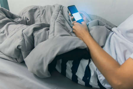 Close-up young man on the bed using smartphone at late night, Phone disease and Nomophobia. Healthy...