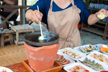 preparing bbq Barbecue hand people Grilling butter on wooden chopsticks on a hot pan, grilled bbq on a hot stove  holiday eating at a restaurantの写真素材