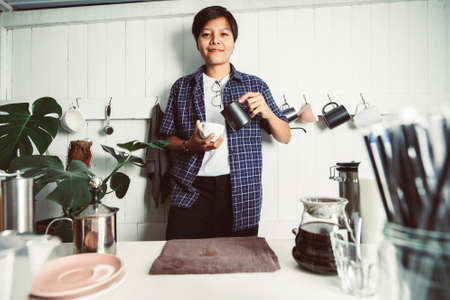 Smiling asian people of a barista poured milk. making hot coffee with equipment, tool brewing on the bar at kitchen homeの写真素材