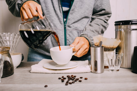 people pouring coffee drip of hot coffee into the cup with equipment, tool brewing with equipment at kitchen home at white kitchen homeの写真素材