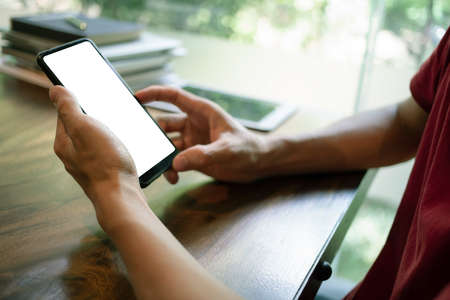Man hand holding a smartphone with Mockup, a blank black screen in the coffee shop. Close upの写真素材