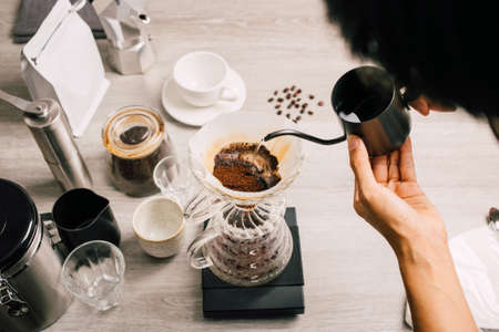 Dripper dripping coffee with filter ground coffee beans with manual stainless steel grinder to make black coffee machine, brewing equipment coffee set on a wooden table top viewの写真素材