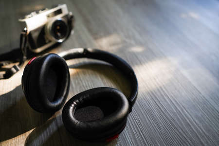 Headphones, and film camera placed on the wood at bedroom in sunset light background. Copy space for your text.の写真素材