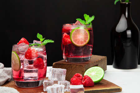 Refreshing summer drink with strawberry slices, lime, and mint leaf  in glasses on dark background beverage sodaの写真素材