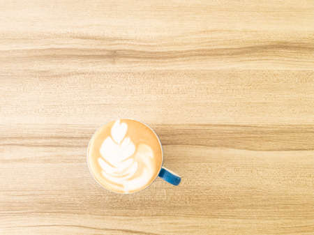 Hand holding cup of latte art coffee homemade on wooden background. copy space for your text