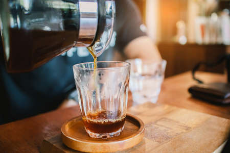 Close up hand of barista pouring, dripping coffee into the glass with equipment tool brewing table on the morning.の写真素材