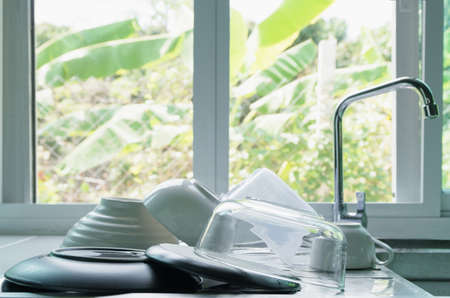 Clean plates, bowls and coffee cups are placed on the sink in the kitchen at home.