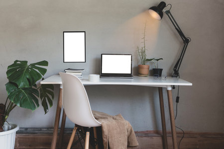 Home office with laptop and chair, book on desk decor white frame as lamp light and monstera tree pot, plants house with wall loft style interior decorations workspace.の写真素材