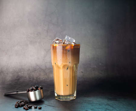 iced latte coffee into a transparent glass with ice. and roasted coffee beans on a black background studio photoの写真素材