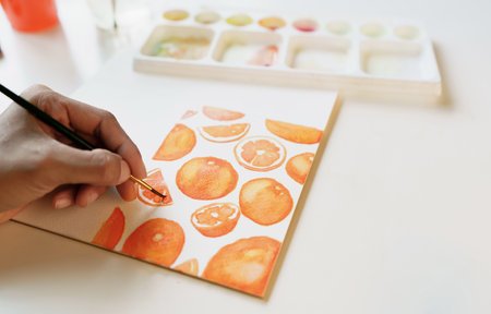 Hand People are using paintbrushes to paint fruit juices, oranges, slice oranges, and watercolors...