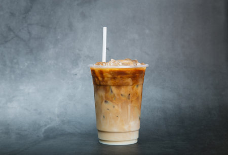 iced coffee in the plastic glass on black marble in studio background summer drink concept