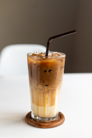 Iced coffee cup with straw on glass cup on white table. Vertical photoの写真素材