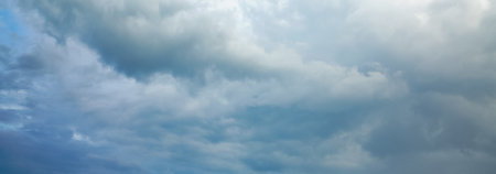 Dark storm clouds gather across the blue sky during the rainy season, forming dramatic shapes as nature signals an approaching storm over the open landscape.の写真素材