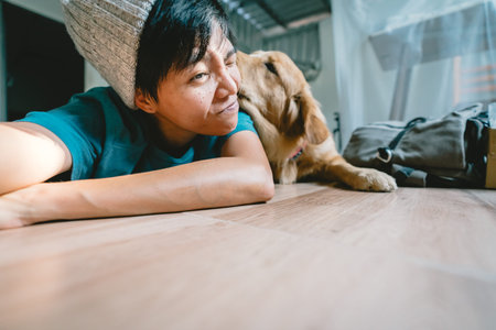 A man takes a selfie with a year-old golden retriever. The dog is licking its owner's face. People and fun playing together looking happily at the camera at home.の写真素材