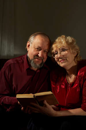 Elderly man and the woman reading the book on a dark backgroundの写真素材
