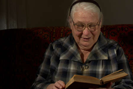 The Elderly women it is keen by reading of the book on a dark backgroundの写真素材